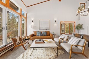 Living area featuring ample seating, flat-screen TV, wood burning fireplace, and balcony access.
