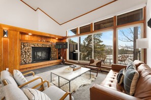 Living area featuring ample seating, flat-screen TV, wood burning fireplace, and balcony access.