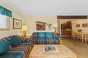 Living area with a wood burning fireplace, workspace, queen sleeper sofa, and balcony access.