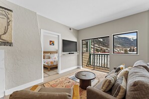 Living area featuring a flat-screen TV, queen sleeper sofa, and access to the private balcony.