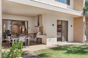 Covered patio with built-in grill, outdoor dining, and direct indoor access