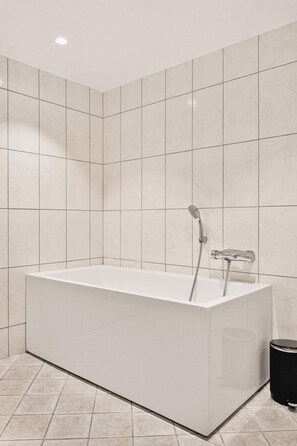 Contemporary bathroom featuring a sleek white tub and matching fixtures.