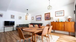Brava Suite by LovelyStay offers a stylish and cozy interior. Enjoy meals at the elegant wooden dining table, unwind on the spacious sofa, and relax with your favorite shows on the large TV. #freewifi #madeiraisland