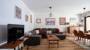 Brava Suite by LovelyStay offers a cozy living room with a spacious sofa, perfect for relaxation. Unwind while watching TV in this stylish and comfortable space, designed for a truly enjoyable stay. #smartv #ribeirabrava