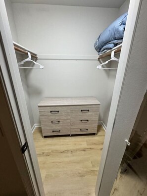 Spacious walk-in closet with shelves, hangers, a dresser, and extra bedding for your convenience.