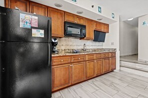 Bright, modern kitchen with sleek countertops, white cabinetry, and stainless steel appliances. Fully equipped with essentials, it features a clean design with coastal accents. Ample lighting and open space make it perfect for cooking and gathering.