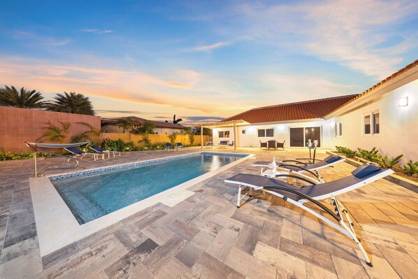 Sunset poolside views with comfortable loungers.


