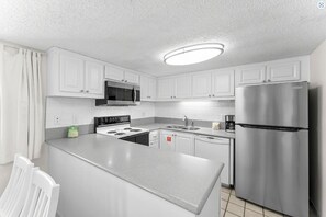 Enter the fully equipped kitchen with a spacious peninsula perfect for prep or serving the family.