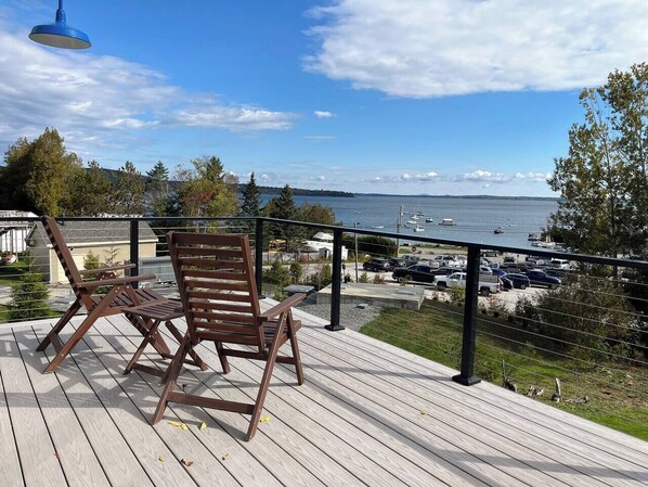 Unwind on a deck with serene ocean views, sailboats, and Blue Hill.