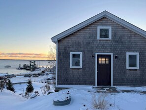 Snowy cottage with harbor sunrises, cozy vibes, and winter charm—your perfect escape awaits.