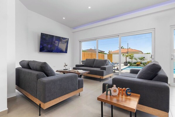 Experience comfort and style in our cozy living room, featuring a plush sofa, a sleek TV, and a large window that offers stunning views of the pool. Perfect for relaxing and unwinding after a day of adventure!