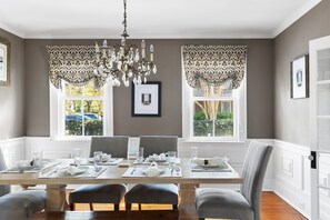 A timeless chandelier, classic wainscoting, and warm wood tones set the stage for cozy gatherings around the table.