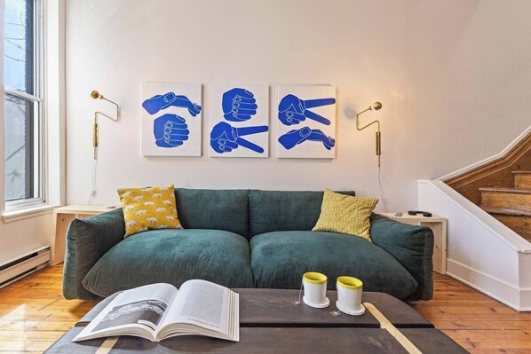 Unwind in this stylish living room with a plush green sofa, modern artwork, and warm ambient lighting, perfect for relaxing after a day of exploring.