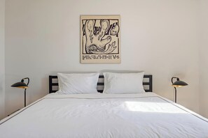 Drift into relaxation in this minimalist bedroom, featuring a plush king bed, crisp white linens, and stylish modern lighting—perfect for a restful stay.