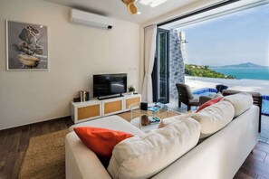 The living room is designed for relaxation and entertainment, featuring a smart TV that provides access to international channels and popular streaming services. 