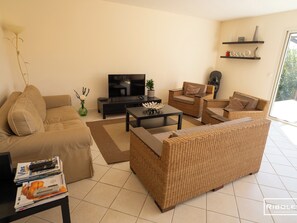 Air-conditioned living room opening onto the garden with sofas, television, wifi