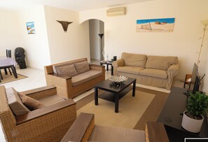 Air-conditioned living room opening onto the garden with sofas, television, wifi