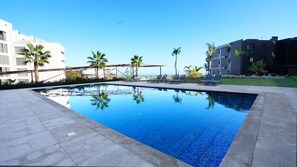 Large shared pool in a modern complex, surrounded by lush greenery and stylish sun loungers. A perfect retreat for relaxation under the Madeira sun #outdoorpool #funchal