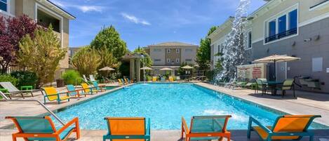 Dive into pure bliss with this stunning year-round heated pool, complete with a cascading water feature, vibrant lounge chairs, and lush surroundings
