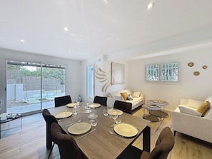 L'espace salon-salle à manger baigne de lumière naturelle, avec une exposition idéale pour une soirée conviviale. Les canapés offrent un coin détente parfait pour discuter après un bon repas.