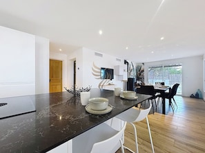 Cet espace de vie moderne et lumineux est parfait pour des soirées conviviales. L'îlot central offre un espace pratique pour cuisiner ou s'installer pour un repas rapide.