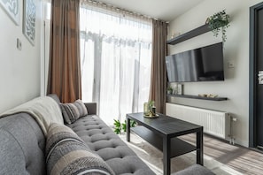 Cozy studio featuring a sleek kitchen, stylish dining space, and comfy sofa. Bright, modern design ideal for a comfortable and relaxing stay.
