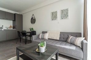 Bright and modern apartment with a full kitchen, dining area, and comfy couch. Perfect for a stylish city stay with natural touches and smart decor.