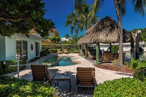 A lush tropical retreat featuring a pool, tiki hut, and lounge seating, perfect for soaking up the Florida Keys sunshine.