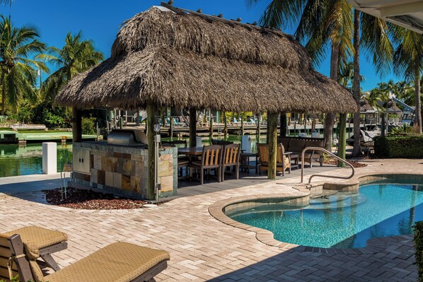Relax in the shaded tiki hut while enjoying the sparkling pool, outdoor seating, and serene canal views.