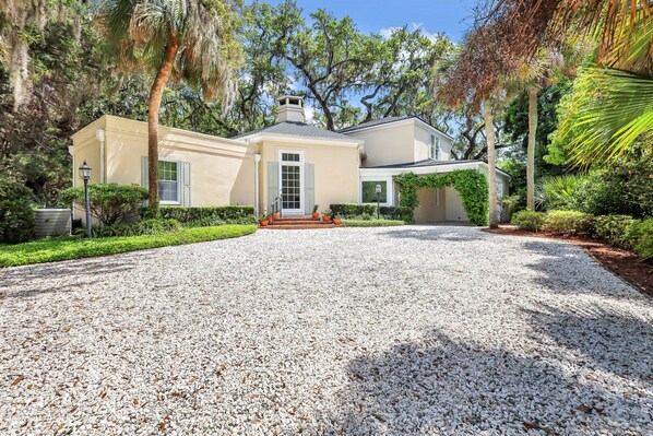 The property has a beautiful entry and expansive driveway with lots of greenery.