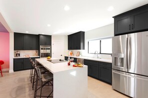 Fully equipped kitchen with stainless steel appliances and a kitchen island with bar seating for 4 guests.