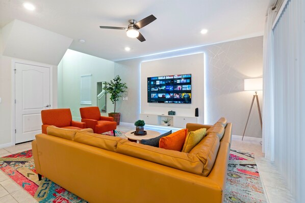 Bright and spacious living room with large windows, plush seating, and a smart TV—perfect for relaxing after theme park days.