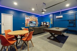 Game room with a classic pool table, perfect for friendly competition, plus a smart TV, couch, and a selection of board games for added fun.