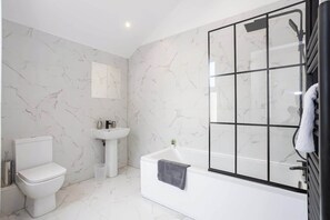 The luxurious bathroom benefits from a toilet, sink and bath with an overhead shower.