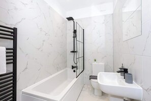 The luxurious bathroom benefits from a toilet, sink and bath with an overhead shower.