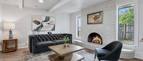 Unwind by the cozy fire in this designer living room with plush seating and natural light.