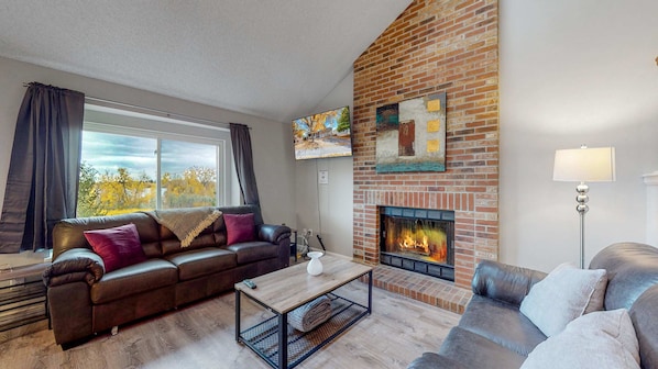 A warm and inviting living room, complete with a cozy fireplace and stunning outdoor views! 🔥🛋️✨