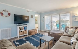 This welcoming living area serves as the heart of your beach retreat. The cozy sectional sofa, large television, and stylish decor create a relaxed atmosphere.