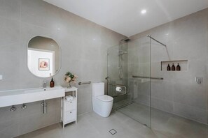 This thoughtfully designed bathroom prioritizes accessibility, featuring grab bars and a spacious walk-in shower for added comfort and convenience.