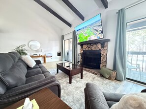 Bright and open living room with cozy seating, wood-burning fireplace, and smart TV
