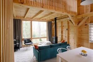 Living and dining area.  Large windows look out to forest and glimpses of water.