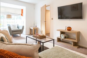 Cosy living room with a comfy sofa and TV for relaxing, plus a well-arranged space that doubles as an ideal work area—perfect for both unwinding and staying productive.