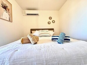 Le mur blanc épuré contraste avec les touches de décoration, créant une ambiance paisible. Détendez-vous sous la climatisation, entouré de détails artistiques subtils pour une nuit reposante. Grand lit 160 X 200 