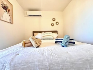 Le mur blanc épuré contraste avec les touches de décoration, créant une ambiance paisible. Détendez-vous sous la climatisation, entouré de détails artistiques subtils pour une nuit reposante. Grand lit 160 X 200