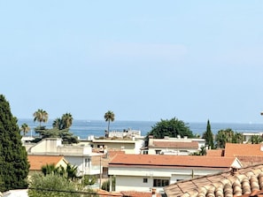 Charmante loggia avec un aperçu sur la mer. Ce petit salon intime, joliment décoré avec des rideaux en macramé et des touches de bois naturel, est l'endroit parfait pour profiter d'un moment de calme et de détente.