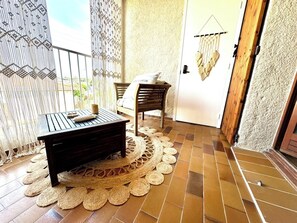 Charmante loggia avec un aperçu sur la mer. Ce petit salon intime, joliment décoré avec des rideaux en macramé et des touches de bois naturel, est l'endroit parfait pour profiter d'un moment de calme et de détente. 