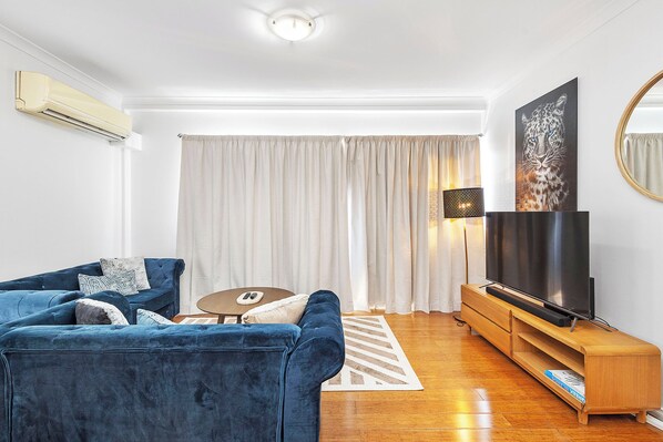  Unwind in a spacious living room, featuring a plush blue velvet sofa that invites you to relax and a sleek wooden entertainment center perfect for movie nights.