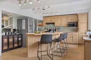 Fully stocked kitchen with dishwasher, coffee station, and breakfast bar seating