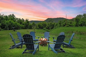 The grassy area down by the water includes an 8 person fire pit, yard games, wicker swing, kayaks, and tubes.