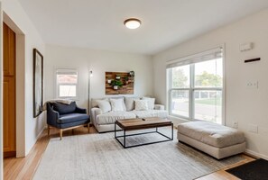 Spacious living area with comfortable seating, smart TV and plenty of natural light